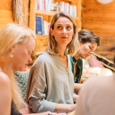 A group of people gathered in a sunlit retreat space for a personal development workshop